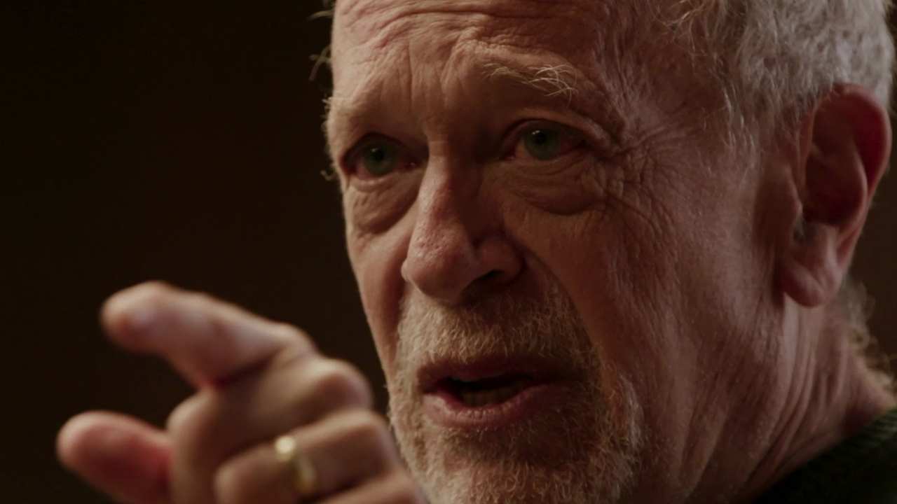 a man with a beard speaking and pointing